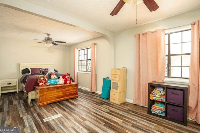 bedroom featuring ceiling fan, a textured ceiling, baseboards, and wood finished floors