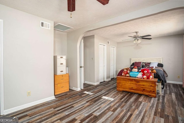 bedroom with visible vents, arched walkways, baseboards, and dark wood-style flooring