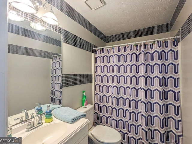 bathroom featuring a textured ceiling, toilet, vanity, and a shower with curtain