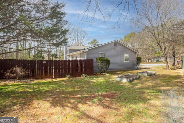 view of side of home featuring a garden, a lawn, and fence