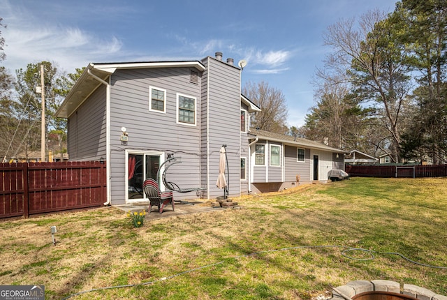 rear view of house featuring a yard, a fenced backyard, and a chimney