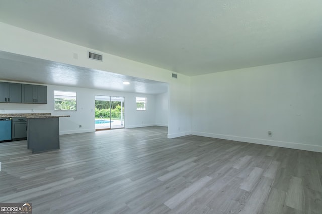 unfurnished living room with light wood-style floors, visible vents, and baseboards