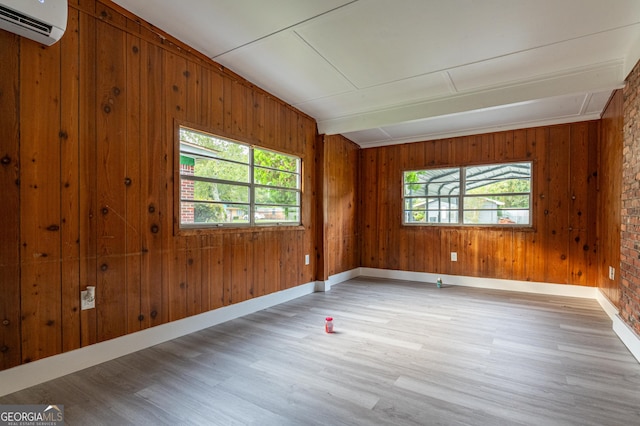 unfurnished room with light wood-style flooring, a wall mounted air conditioner, and baseboards