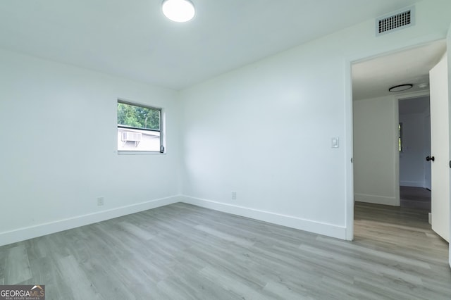 empty room featuring visible vents, light wood-style floors, and baseboards