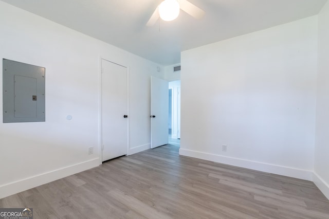 unfurnished bedroom with visible vents, electric panel, wood finished floors, baseboards, and ceiling fan