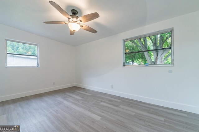 unfurnished room featuring ceiling fan, light wood-style floors, and baseboards