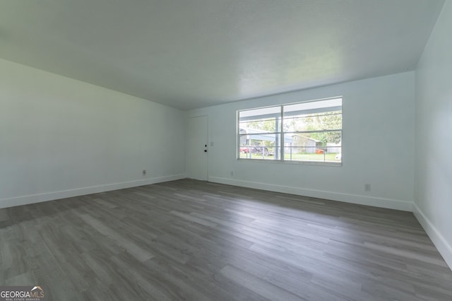 empty room with dark wood finished floors and baseboards