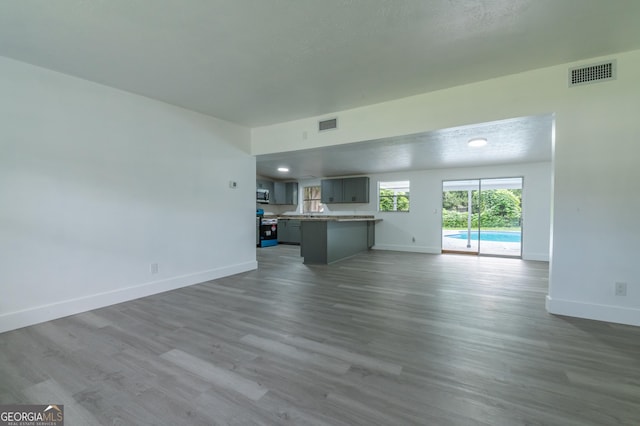 unfurnished living room featuring visible vents, baseboards, and wood finished floors