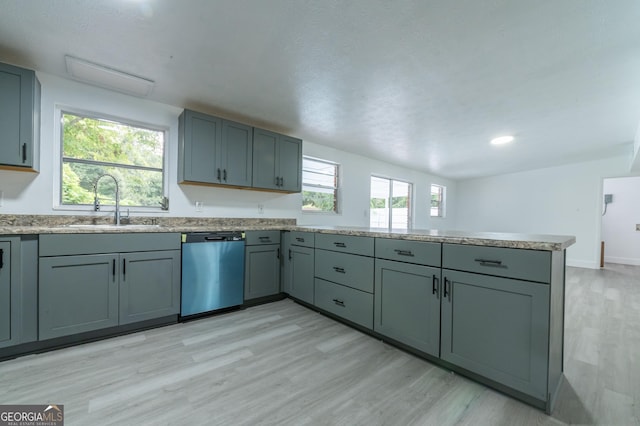 kitchen featuring a sink, stainless steel dishwasher, light wood-style floors, a peninsula, and baseboards