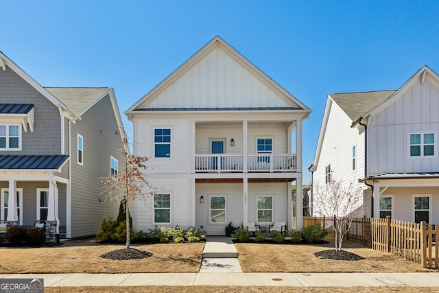 view of front facade featuring a balcony, fence, a standing seam roof, board and batten siding, and metal roof