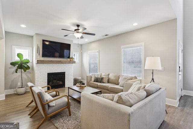 living area with visible vents, baseboards, wood finished floors, and a fireplace