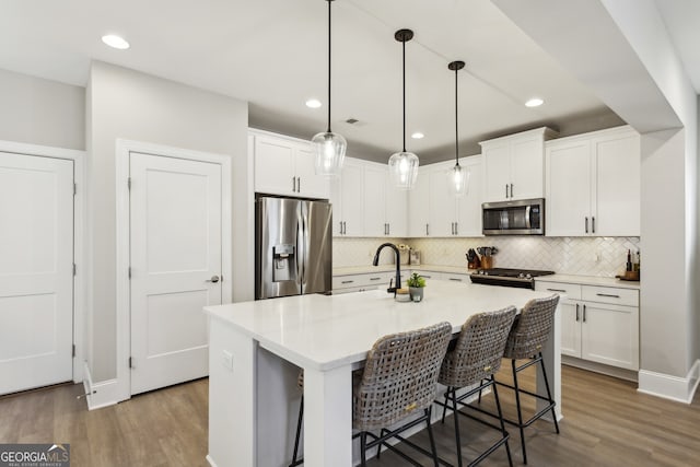 kitchen featuring appliances with stainless steel finishes, wood finished floors, light countertops, and white cabinetry