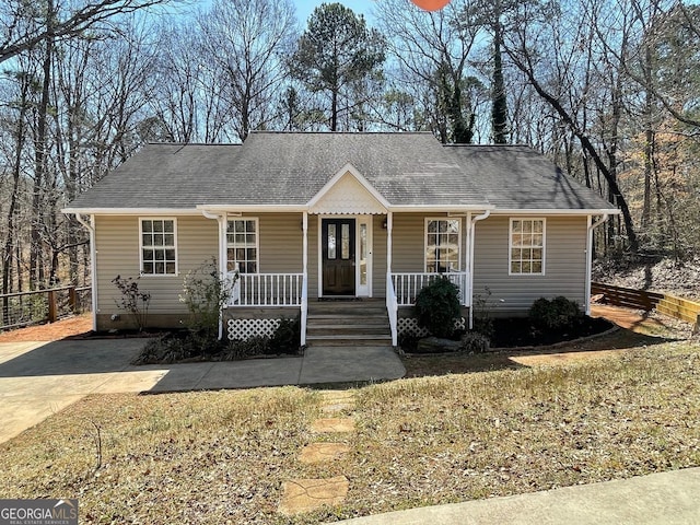 view of front of home featuring fence, covered porch, and roof with shingles