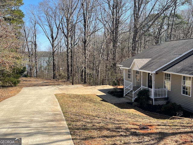 view of yard featuring covered porch and a wooded view