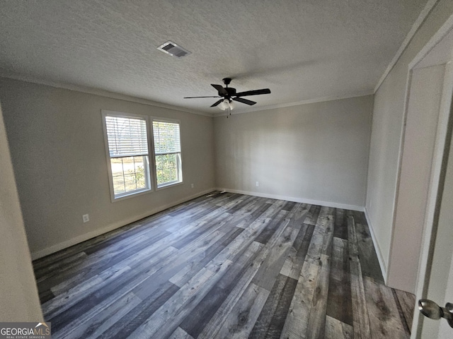 spare room featuring visible vents, a textured ceiling, dark wood finished floors, crown molding, and baseboards