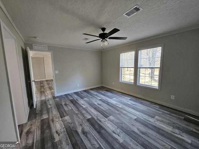 spare room featuring a ceiling fan, dark wood-style floors, visible vents, baseboards, and ornamental molding