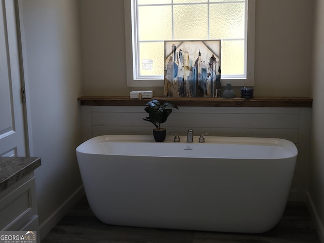 bathroom featuring a healthy amount of sunlight, baseboards, and a freestanding bath