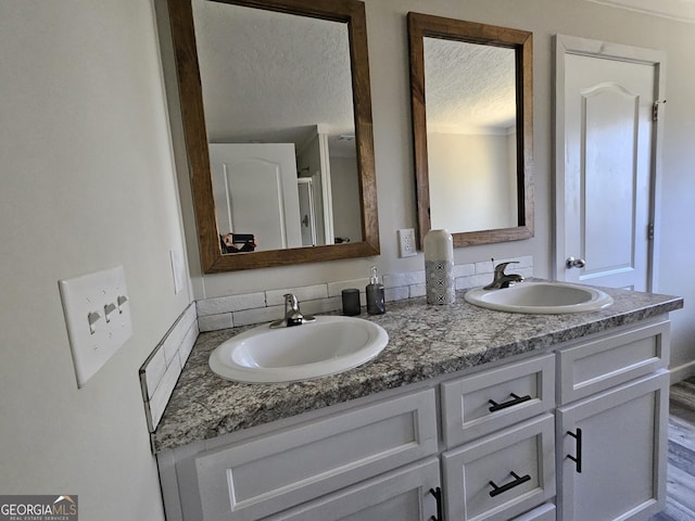 full bathroom featuring a sink, a textured ceiling, and double vanity