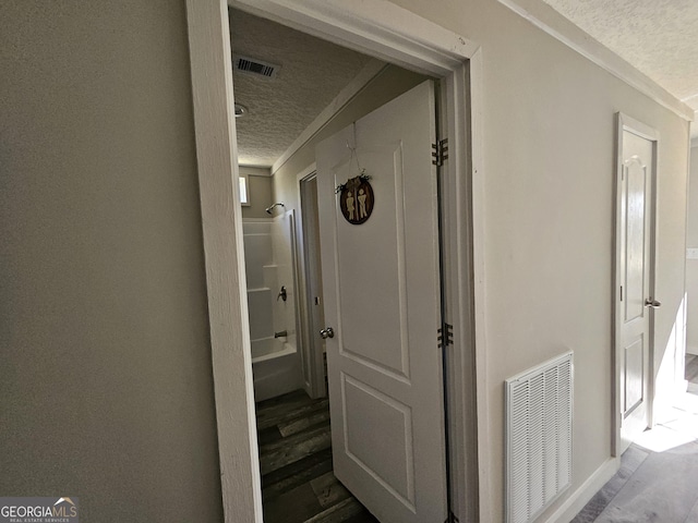 corridor with visible vents, a textured ceiling, and wood finished floors