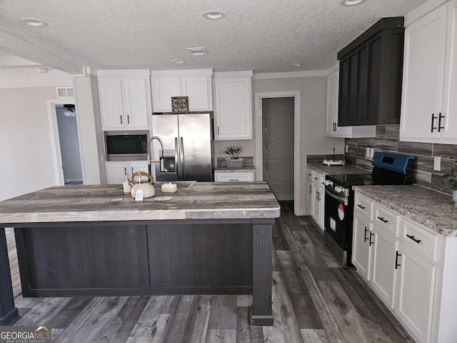 kitchen featuring visible vents, dark wood-type flooring, white cabinets, appliances with stainless steel finishes, and tasteful backsplash