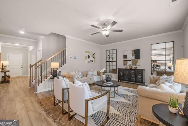 living area with a ceiling fan, wood finished floors, stairway, crown molding, and baseboards