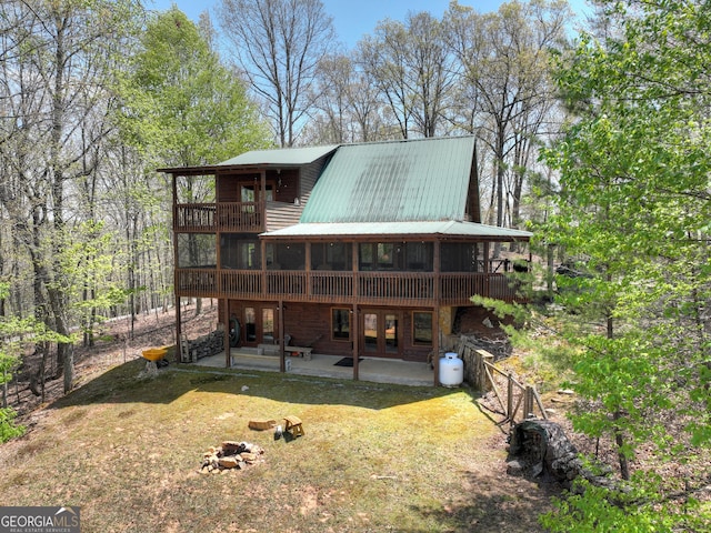 back of property with a balcony, french doors, a yard, a patio, and metal roof