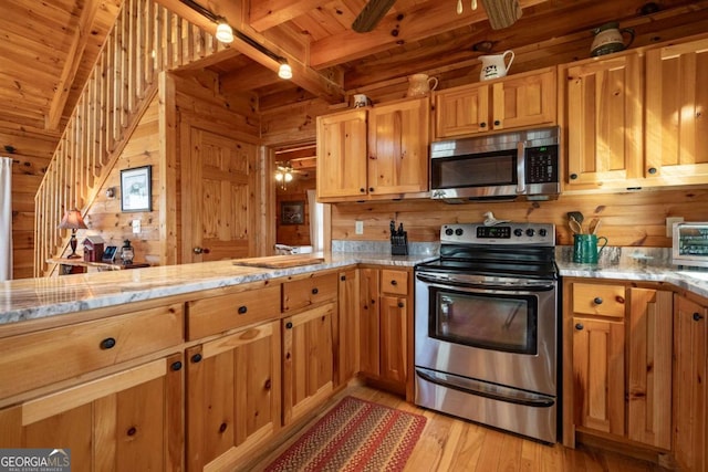 kitchen featuring beam ceiling, wooden walls, appliances with stainless steel finishes, and wood ceiling