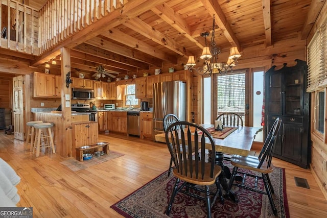 dining space with plenty of natural light, wood walls, and light wood-type flooring