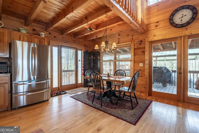 dining room with a wealth of natural light, wooden walls, and light wood finished floors