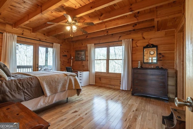 bedroom featuring light wood-style flooring, multiple windows, and wood walls