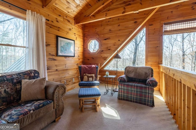 living area with plenty of natural light, wood walls, vaulted ceiling with beams, and carpet floors