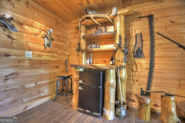 interior space featuring wood walls, wood finished floors, indoor bar, freestanding refrigerator, and wood ceiling