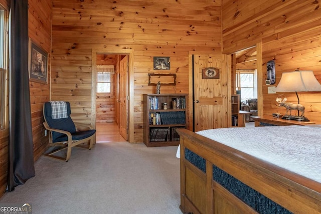 bedroom with light carpet, multiple windows, wood walls, and a towering ceiling