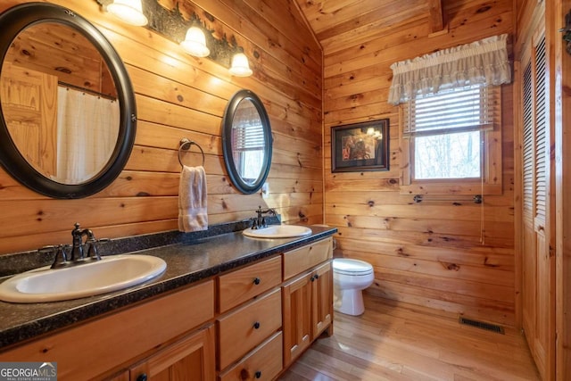 full bathroom featuring a sink, visible vents, toilet, and wooden walls