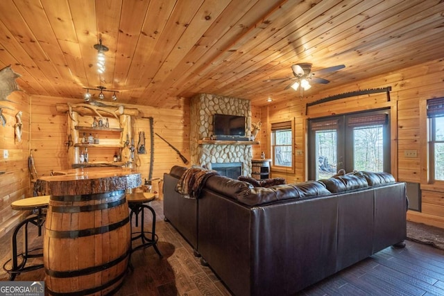 living room with dark wood-type flooring, wooden walls, a fireplace, and wooden ceiling