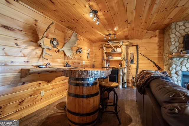 bar with wood walls, wooden ceiling, rail lighting, and dark wood-style flooring