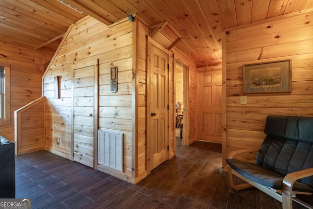 sitting room featuring dark wood-type flooring, wooden walls, wood ceiling, and visible vents