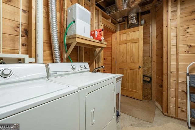 laundry room with laundry area, separate washer and dryer, and wood walls