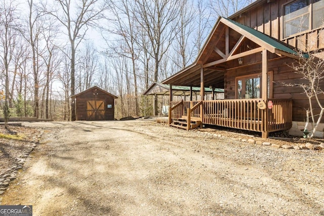 view of side of property with an outbuilding, driveway, a garage, a deck, and a storage shed