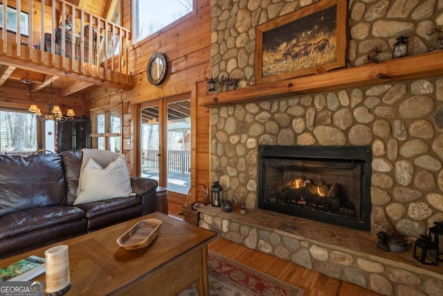 living area featuring a stone fireplace, wood finished floors, and a healthy amount of sunlight