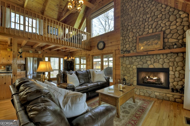living area with wooden ceiling, light wood-style floors, beam ceiling, and ceiling fan with notable chandelier
