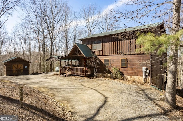 view of front facade with a deck, driveway, an outdoor structure, and board and batten siding