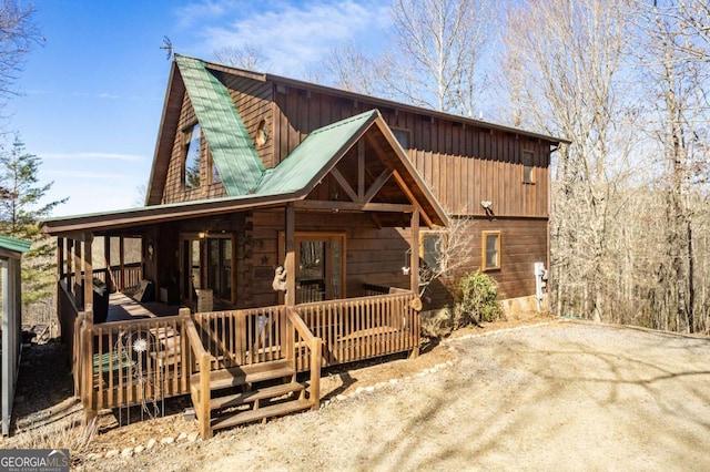 back of property featuring a porch and metal roof