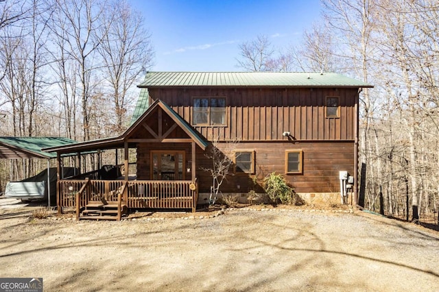 back of house featuring metal roof, board and batten siding, and dirt driveway