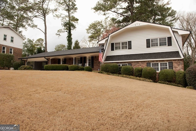 view of front of home featuring brick siding, a gambrel roof, a shingled roof, and a front lawn