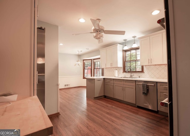 kitchen featuring visible vents, decorative backsplash, stainless steel dishwasher, dark wood-style floors, and a sink