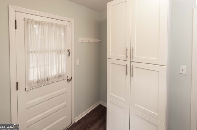 doorway featuring dark wood-style floors and baseboards