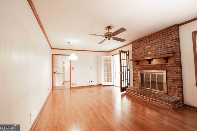 unfurnished living room featuring wood finished floors, crown molding, a fireplace, and baseboards