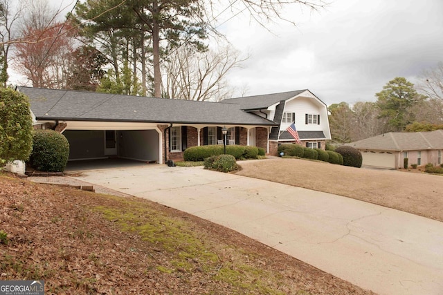 split level home with brick siding, a shingled roof, a gambrel roof, a garage, and driveway