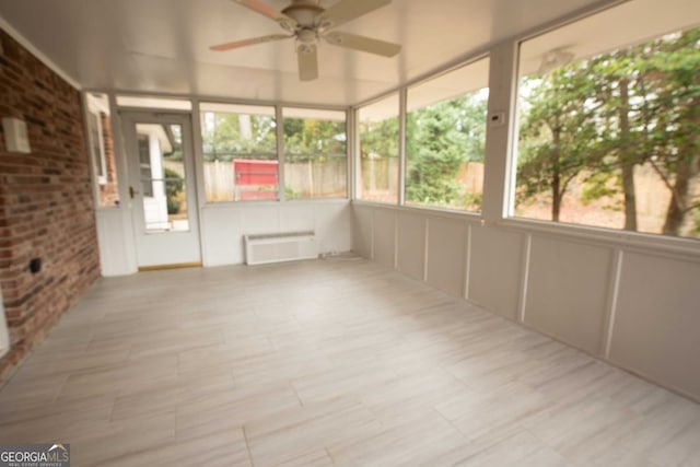 unfurnished sunroom featuring ceiling fan and radiator heating unit